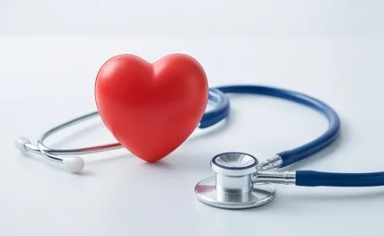 A red heart shape resting beside a stethoscope